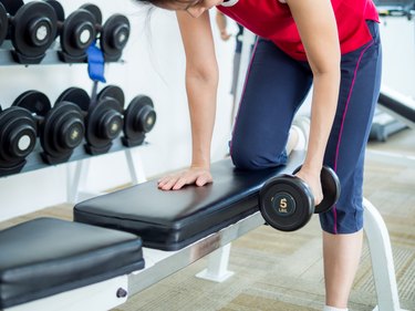 Woman exercising with lifting dumbbell in gym