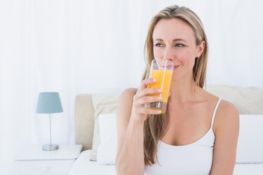 Smiling blonde drinking glass of orange juice