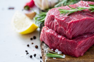 Raw steak and ingredients on wood board