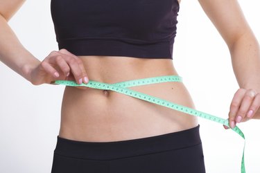 A woman's midsection with measuring tape around her waist