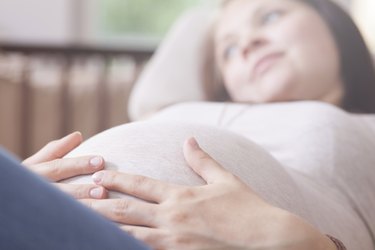 a pregnant person lying down holding their stomach
