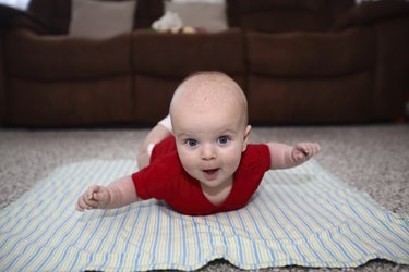 Baby having tummy time with his hands like flying