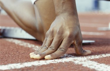 Person kneeling with hands on starting line, Close-up of hand