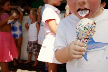 Boy (3-5) eating ice cream, close-up, other children in background