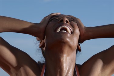 Young female athlete with head in hands laughing