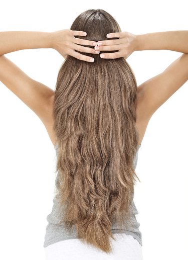 Brunette lady holding long hairs, view from back side