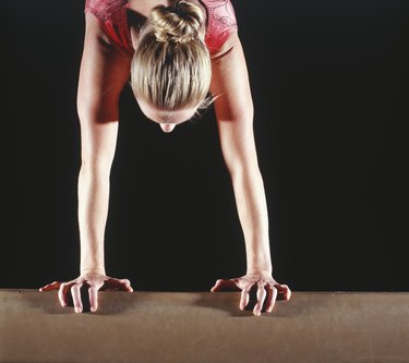 Female gymnast performing handstand on balance beam