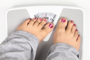 Woman trying to hide what the scale is reading with toes