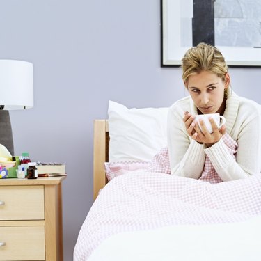 woman sitting in bed with a cup of soup
