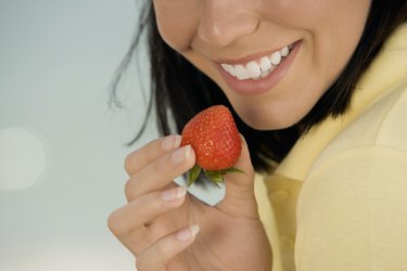 Close-up of a young woman holding a strawberry on the beach