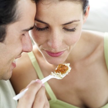 close-up of a young man feeding a young woman with a plastic fork