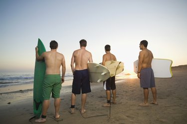 Rear view of multi-ethnic surfers