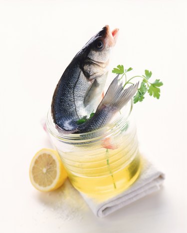 Raw fish, cooking oil, chervil, lemon and napkin on white background, close-up 