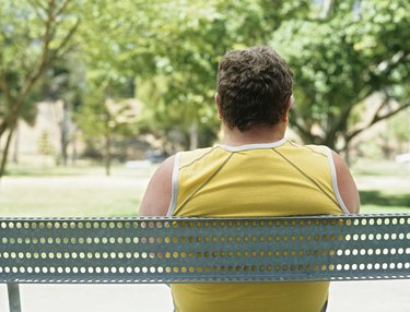 Overweight man sitting on bench in park,rear view