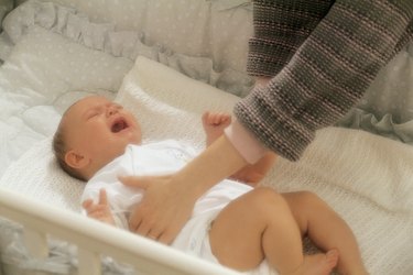 Mother reaching for crying baby in crib