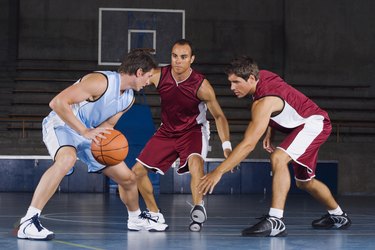 Man dribbling basketball against defenders