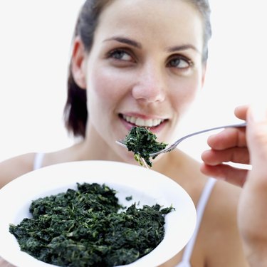 close-up of a woman being fed spinach