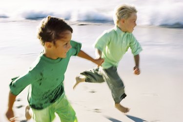 Boys running barefoot on beach