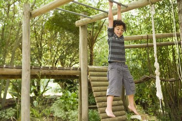 Boy hanging from jungle gym