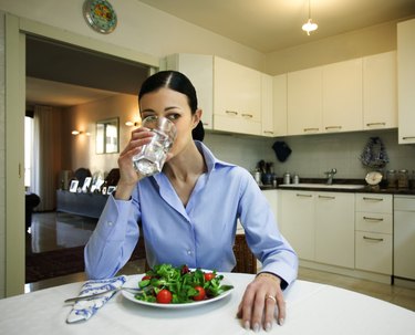 Woman with salad drinking water
