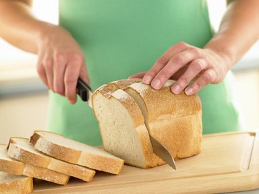 Woman Slicing A Loaf Of White Bread