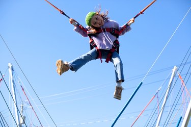 Girl jumping on trampoline with bungee cords