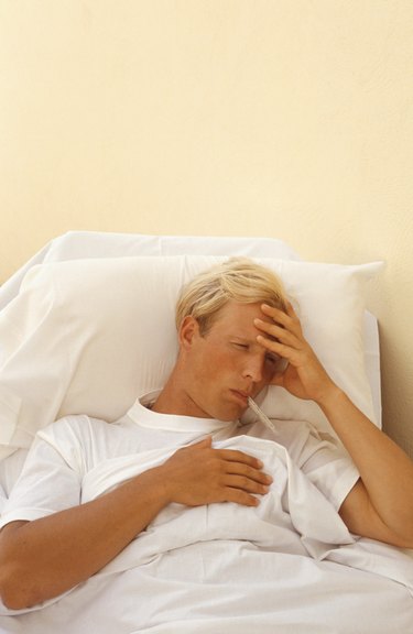 Man in bed with thermometer in mouth