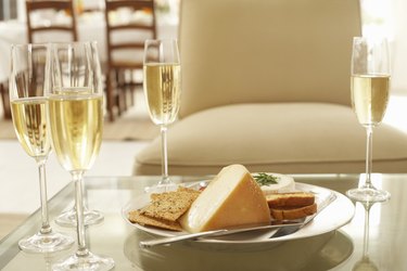 Glasses of wine by plate of cheese and biscuits on coffee table