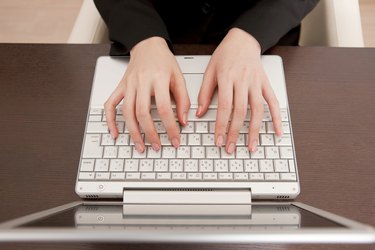 Overhead view of a person's hands typing on a keyboard, to show the concept of thinner fingers