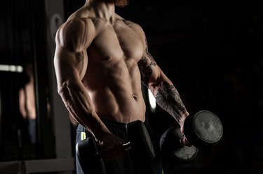 bodybuilder with dumbbells in a gym, exercising with a barbell