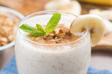 A milkshake with banana, granola and cinnamon in a glass, close-up