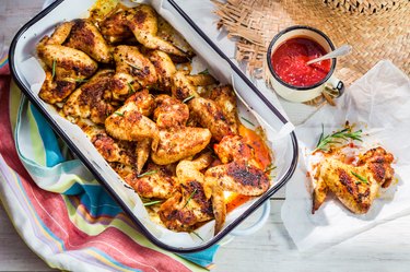 Spicy chicken wings with herbs and sauce in rustic kitchen