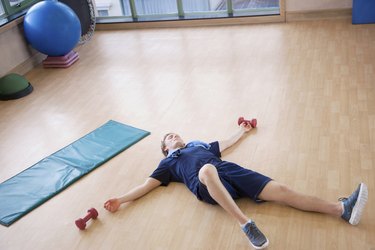 Tired young man lying on his back in the gym