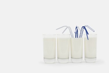 Glasses of milk in a row with drinking straws