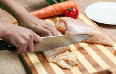 woman's hand cutting chicken breast