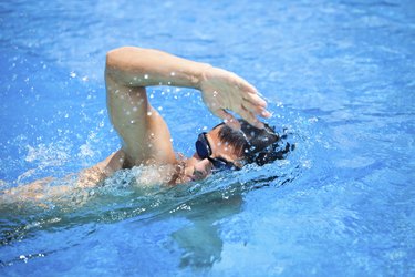 Young man swimming a fast freestyle stroke in a pool