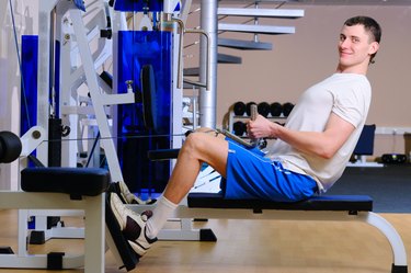 young handsome man is training in gym using a rower