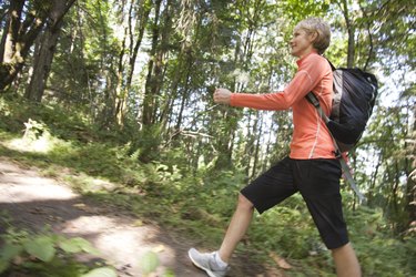 Woman hiking up hill in forest, profile view