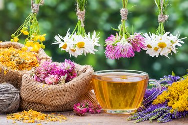 Healing herbs, bags with dried plants and cup of tea