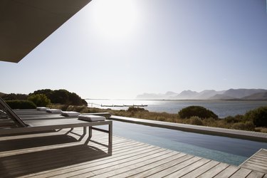 View of sun shining on lake from patio with swimming pool