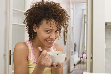 Smiling woman eating bowl of cereal