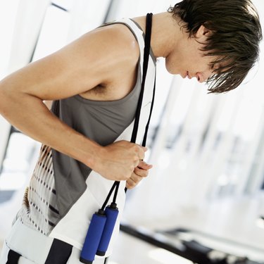 Young man standing with a skipping rope around his neck