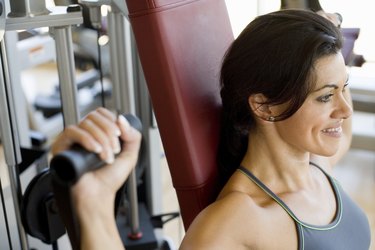 Woman doing Hammer strength machine. Seated chest press exercise