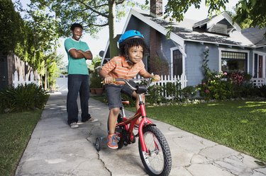 Father teaching boy to ride bicycle