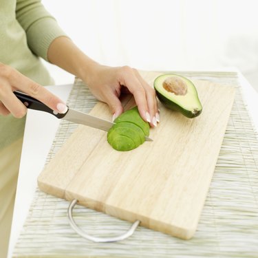 Young woman slicing an avocado with a knife