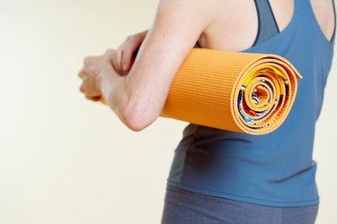 Woman with rolled yoga mat