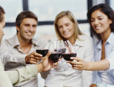four people toasting with red wine