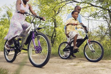 African grandfather teaching grandson to ride a bicycle in park
