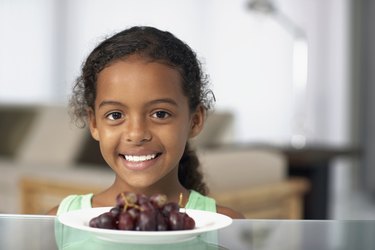 Mixed Race girl with plate of grapes