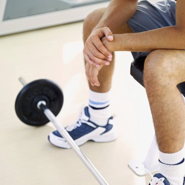 man sitting with a barbell on the floor in front of him